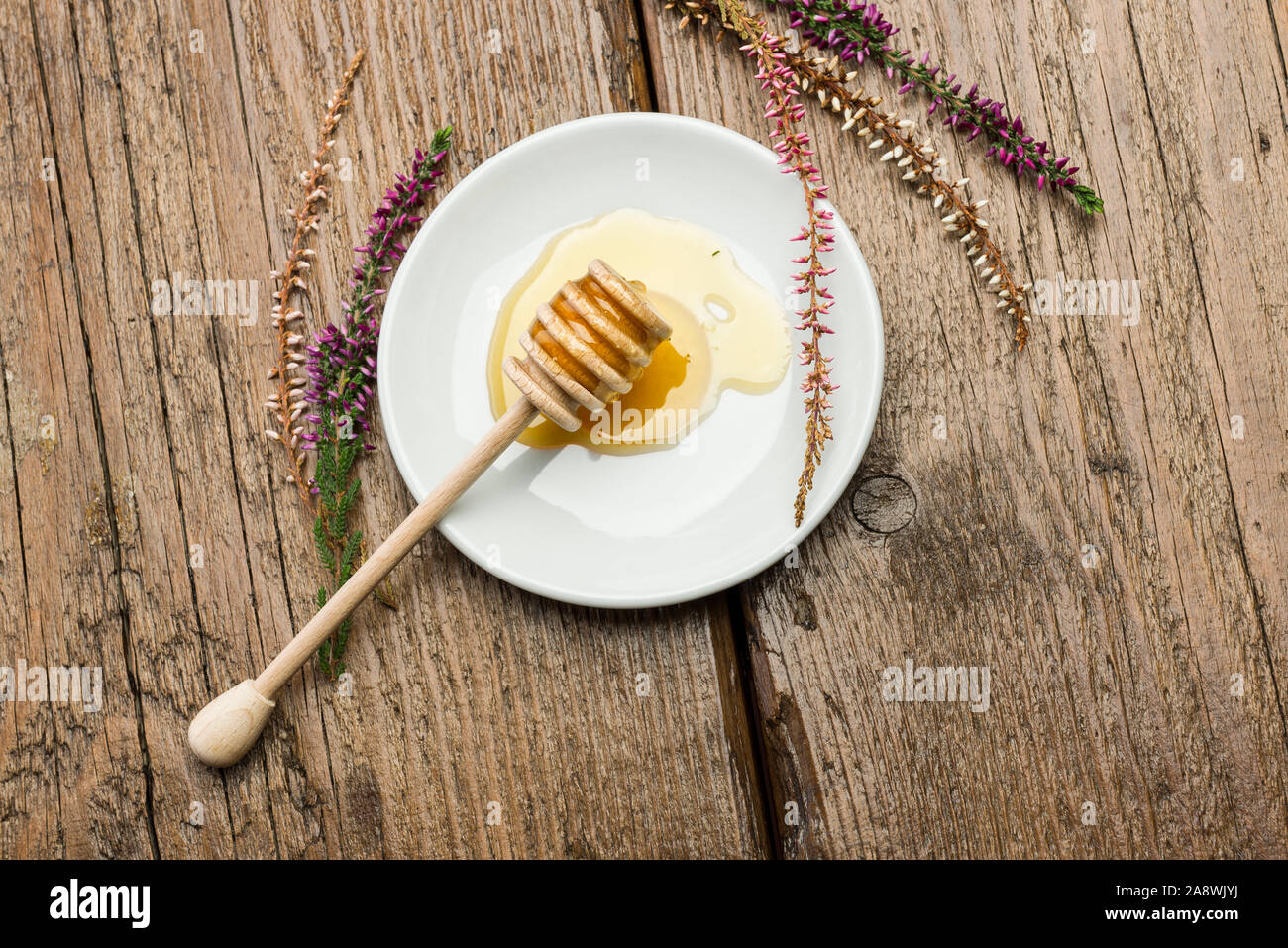 Sur balancier miel miel avec soucoupe sur table en bois avec des fleurs Banque D'Images