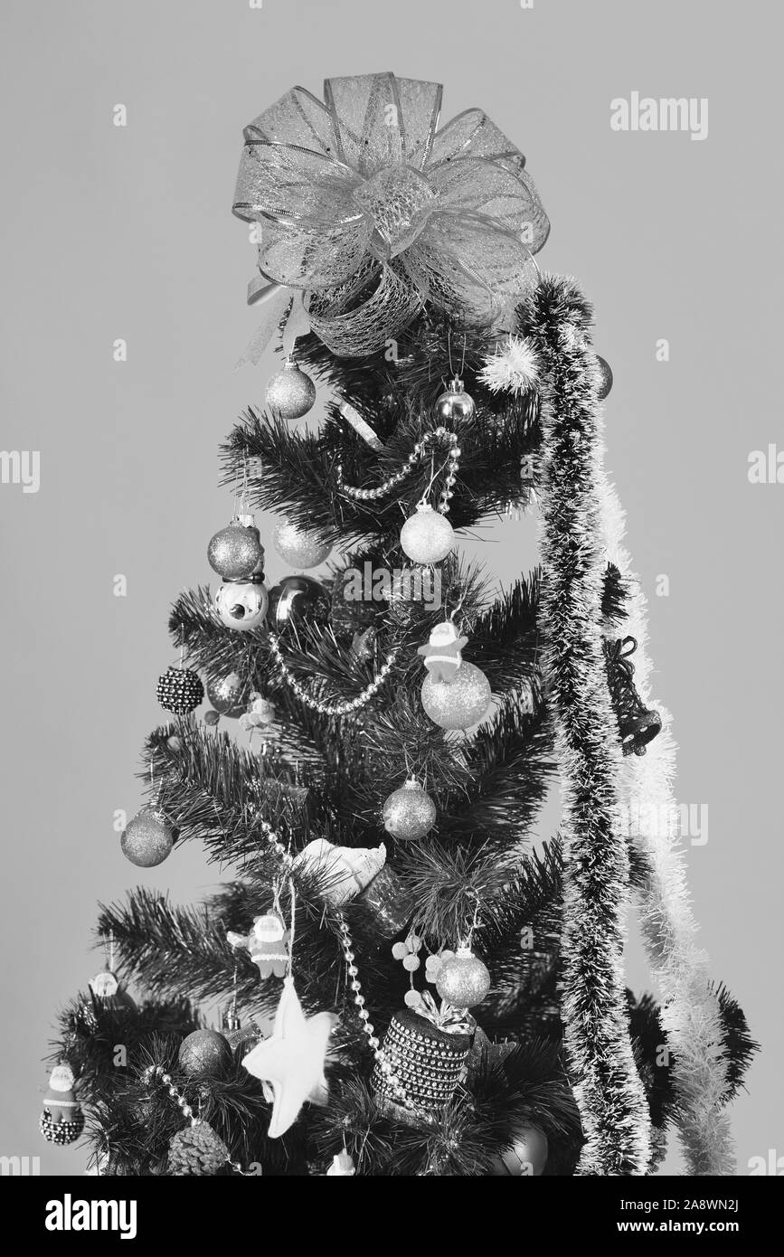 Arbre de Noël avec décor sur fond rouge. Sapin avec boules colorées et jouets sur elle. Archet d'or sur le dessus de symbole de Noël. Concept de vacances et décorations Banque D'Images