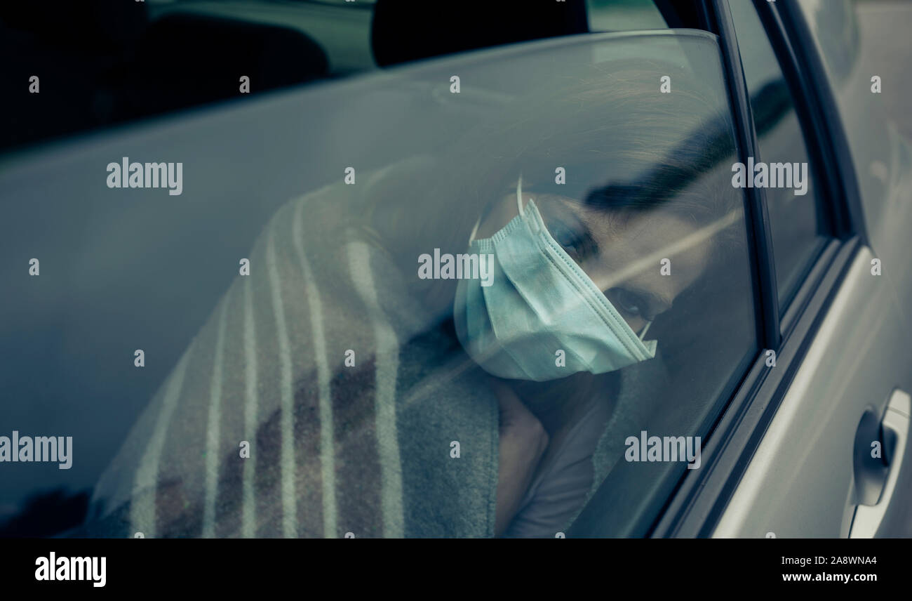 Vue à travers la fenêtre de voiture d'une femme avec masque Banque D'Images
