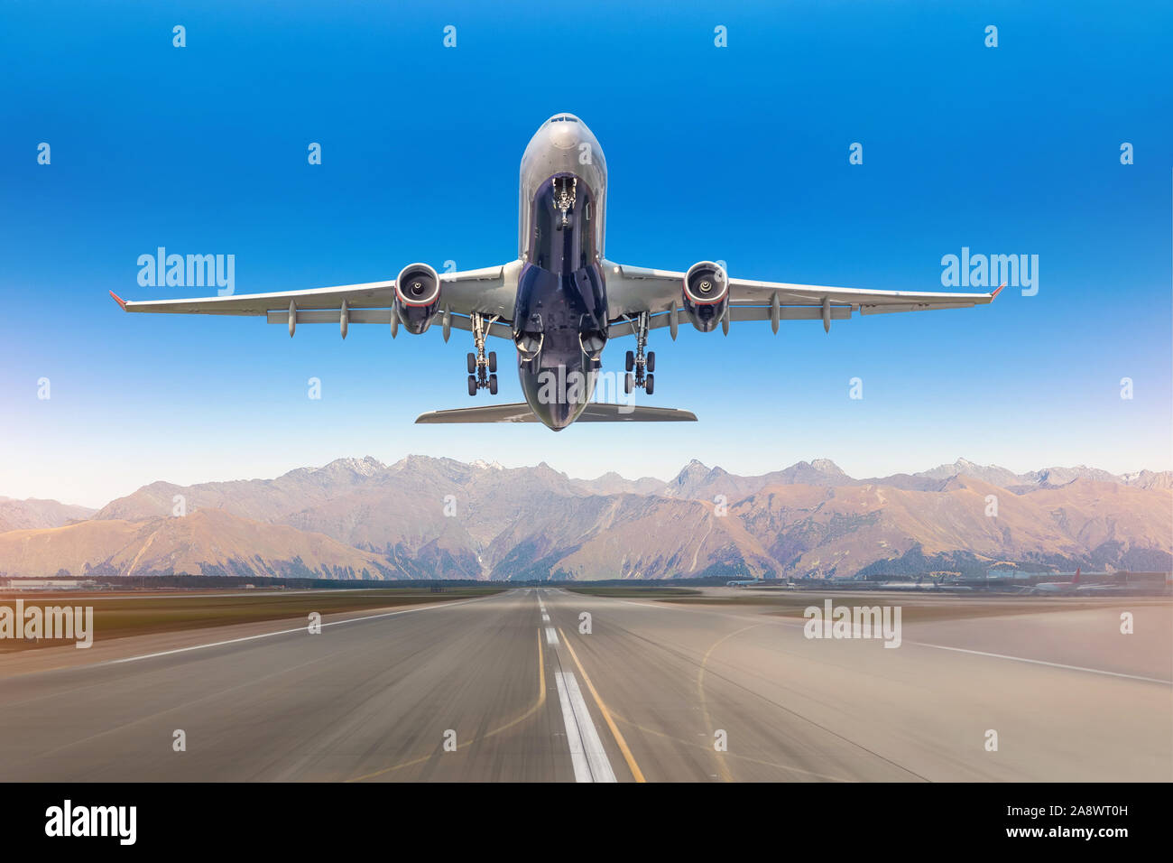 Vue sur la piste de l'aéroport, et d'un décollage d'avions de transport de passagers contre contexte le système de montagne par temps clair Banque D'Images Vue sur la piste de l'aéroport, et d'un décollage d'avions de transport de passagers contre contexte le système de montagne par temps clair Banque D'Images
