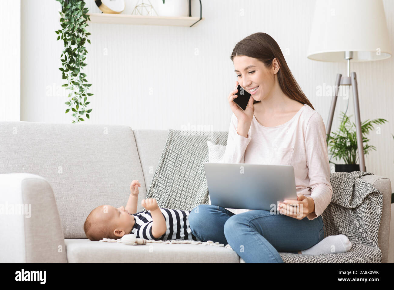 Woman working on laptop à la maison pour s'occuper de son bébé Banque D'Images