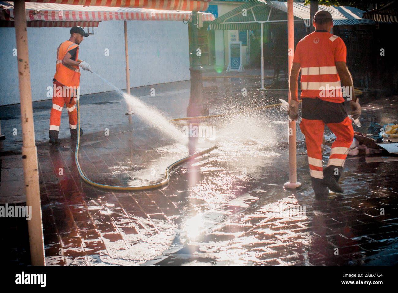 Nice, Provence / France - 28 septembre 2018 : Les travailleurs en combinaisons orange laver la rue après le marché aux fleurs Banque D'Images