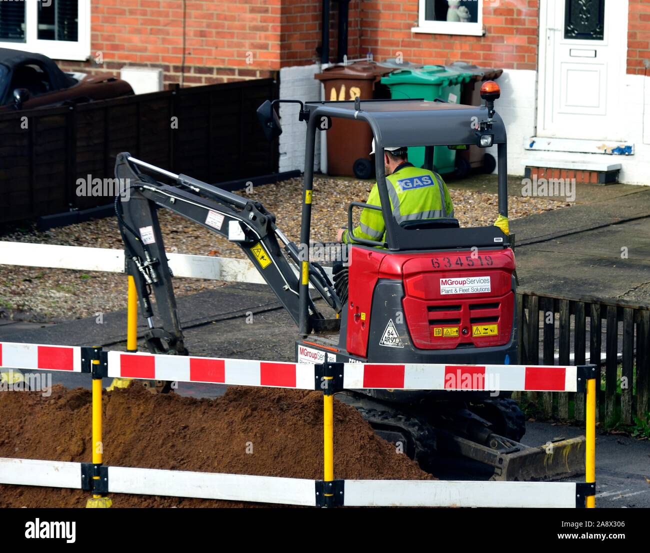 En cours d'excavation de la chaussée avec une Volvo EC18D mini pelle pour remplacer les canalisations de gaz UK Banque D'Images