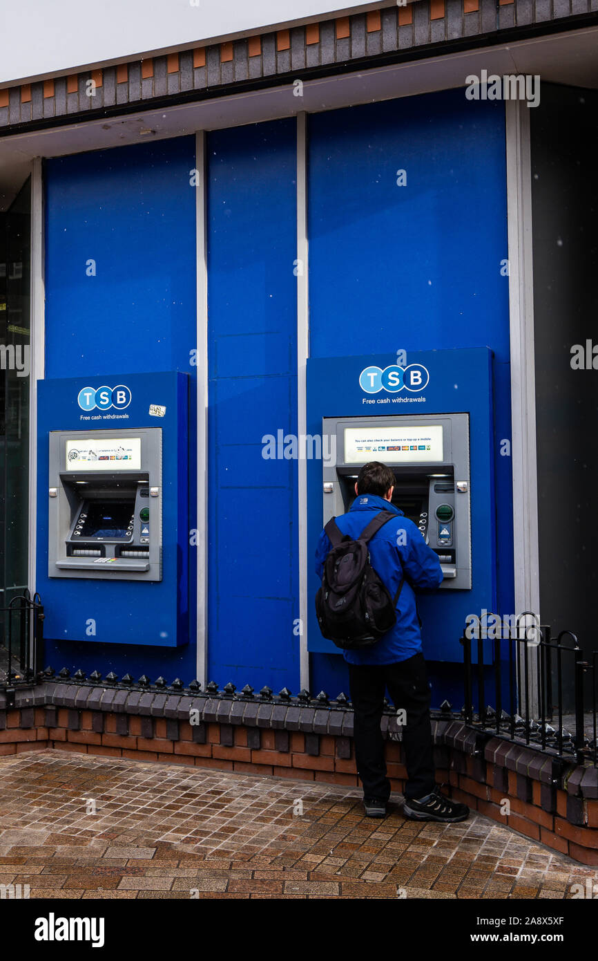 Un homme à l'aide d'un distributeur de billets, distributeur automatique de billets à la banque du BST dans la ville high street, cash machine, retirer de l'argent Banque D'Images