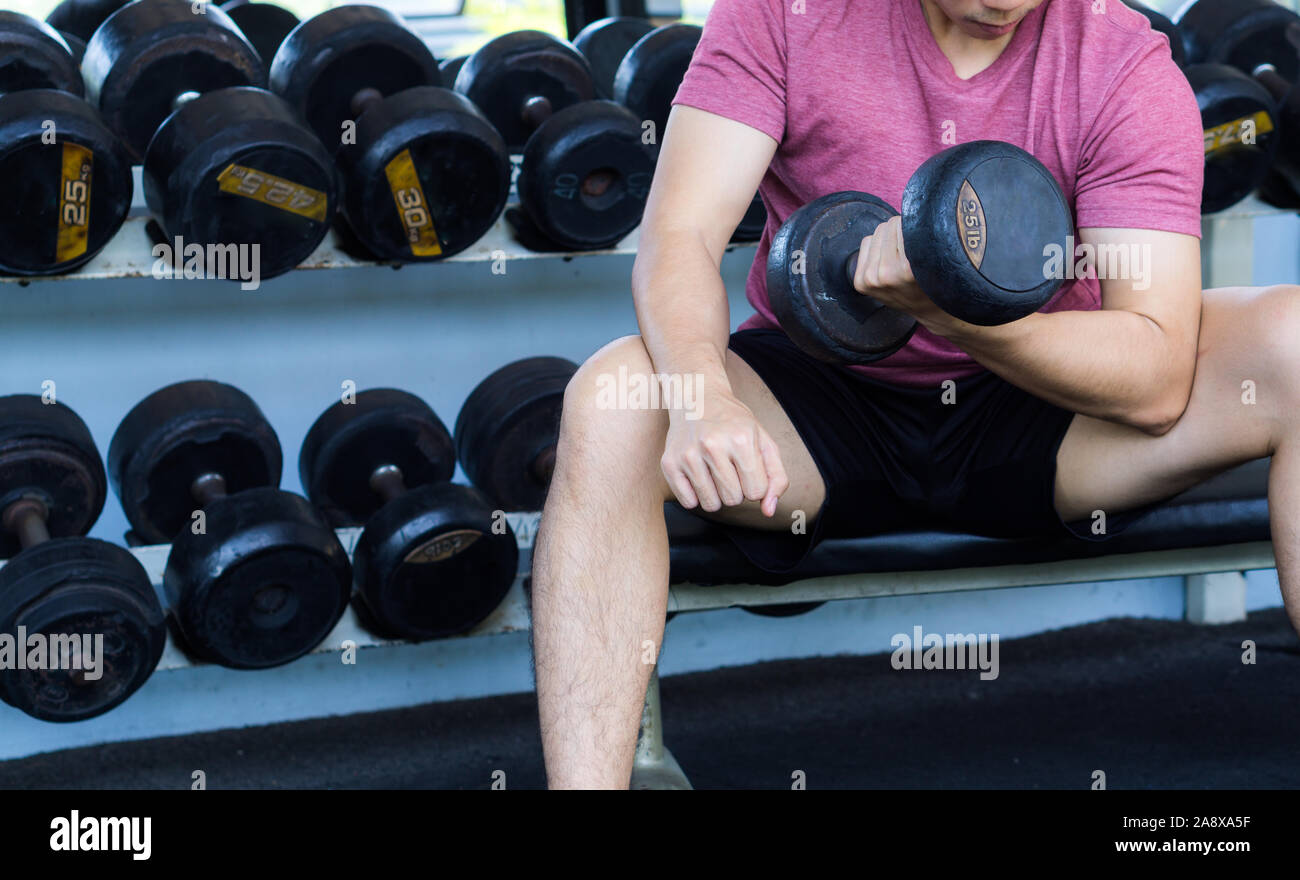 Ce faisant l'homme Fitness biceps curl. Exercice avec haltères curl assis à la salle de sport. La remise en forme. Le sport, la condition physique, santé, mode de vie et de personnes concept Banque D'Images