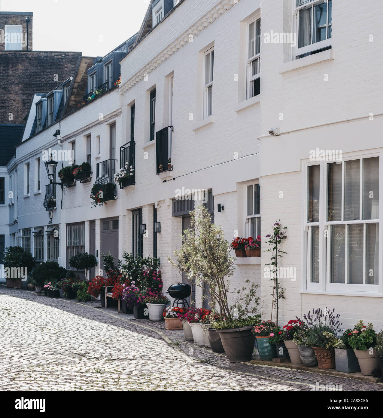 Rangée de maisons typiques mews à Londres, au Royaume-Uni, d'un balcon romantique avec des paniers de fleurs et à l'extérieur. L'immobilier et des biens concept, selective focus. Banque D'Images