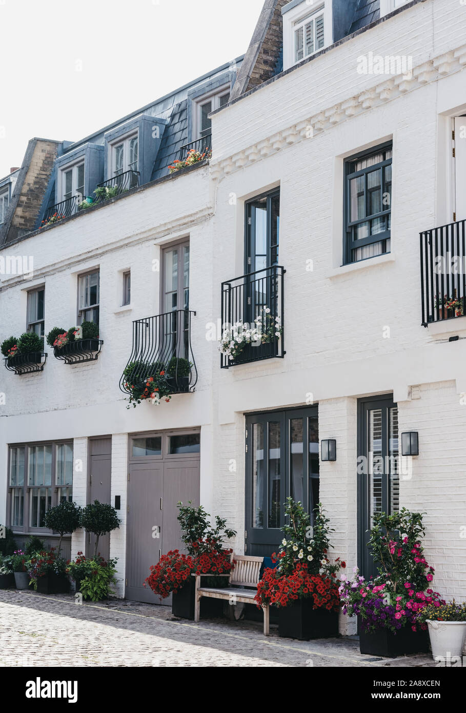 Rangée de maisons typiques mews à Londres, au Royaume-Uni, avec des paniers de fleurs, d'un balcon romantique et garage. L'immobilier et des biens concept, selective focus. Banque D'Images