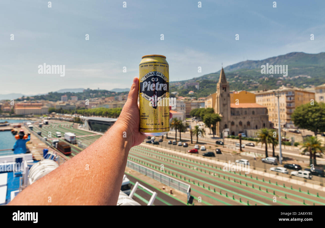 BASTIA, Corse, France - 23 juillet 2019 : la main de l'homme blanc est titulaire d'un peut de Pietra bière Corse Bastia ville port libre avec en arrière-plan. Banque D'Images