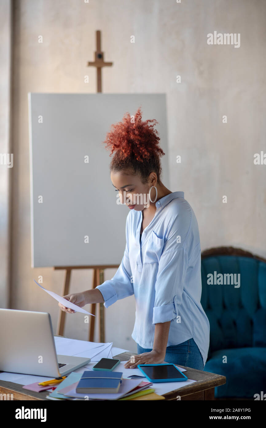 Designer d'intérieur bouclés à lire des documents, debout près de la table Banque D'Images