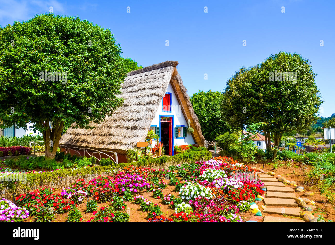 Des maisons traditionnelles en Santana, Madère, Portugal. Maisons en bois triangulaire, représentent une partie de patrimoine portugais. Jardin de devant avec de belles fleurs colorées. Monument touristique. Banque D'Images