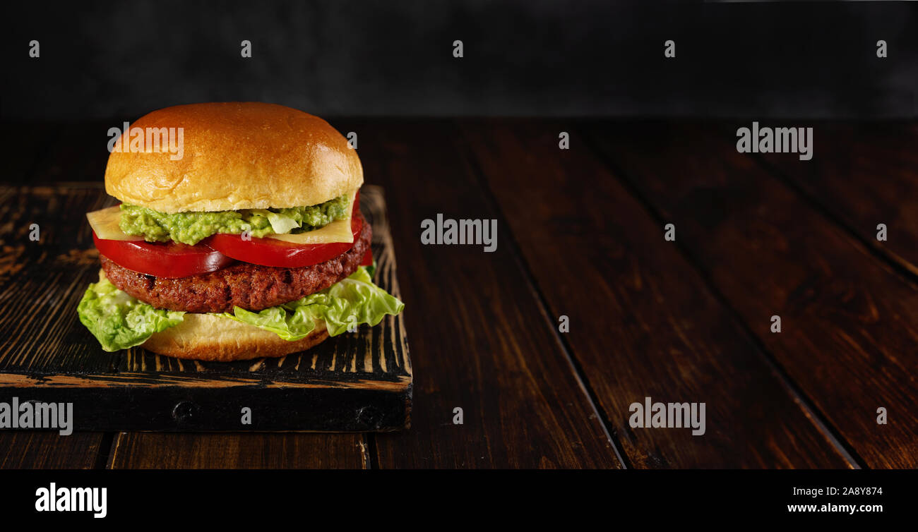 Burger végétarien fait maison sur planche de bois sur fond sombre Banque D'Images