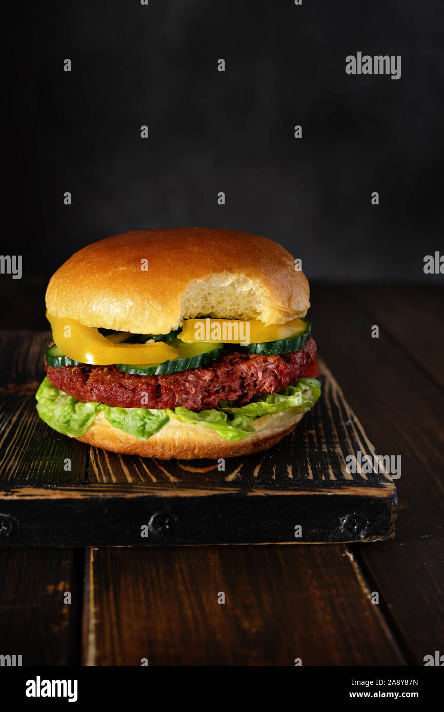 Mordu burger végétarien sur planche de bois sur fond sombre Banque D'Images