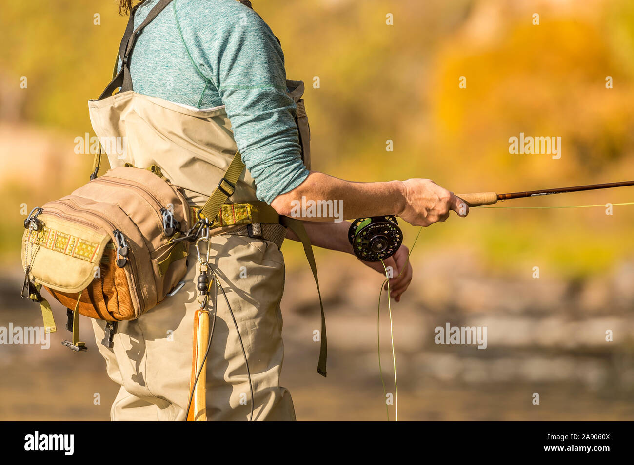 Une femme tient sa canne et moulinet de pêche sous le soleil d'après-midi d'automne dans le nord du Colorado. Banque D'Images