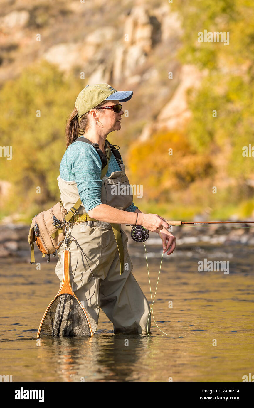 Une femme tient sa canne et moulinet de pêche sous le soleil d'après-midi d'automne dans le nord du Colorado. Banque D'Images