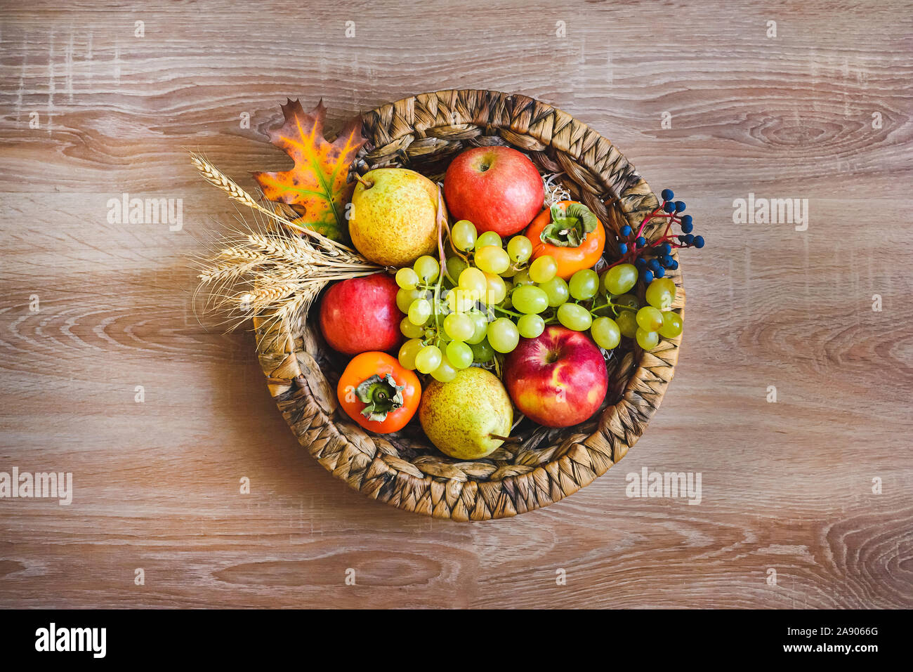 Vue de dessus de divers fruits d'automne colorés dans un panier en osier sur la table en bois. Banque D'Images