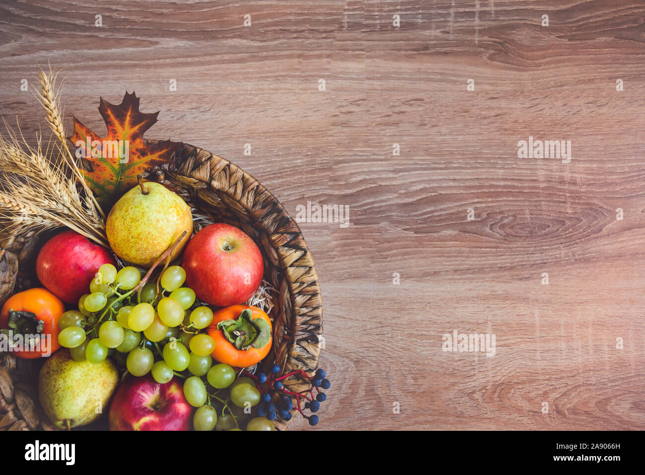 Vue de dessus de divers fruits d'automne colorés dans un panier en osier sur la table en bois. Copier l'espace. Banque D'Images