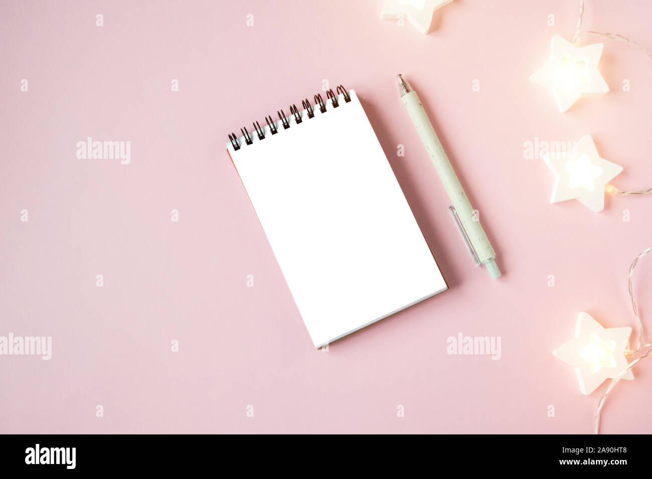 Ordinateur portable blanc feuille sur fond rose avec guirlande Banque D'Images