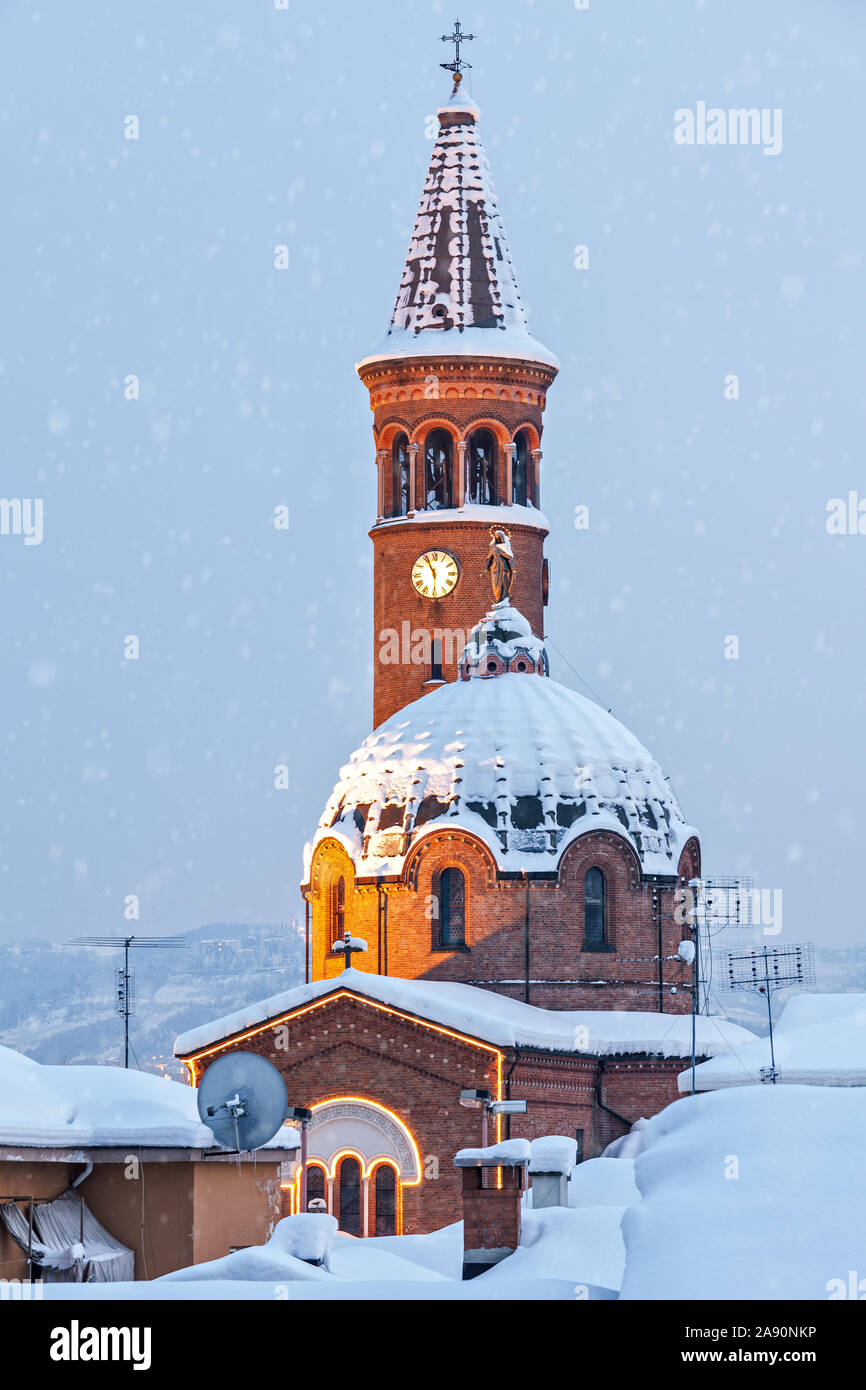 Dome et beffroi de l'église catholique recouverts de neige en ville d'Alba, Piémont, Italie du Nord. Banque D'Images