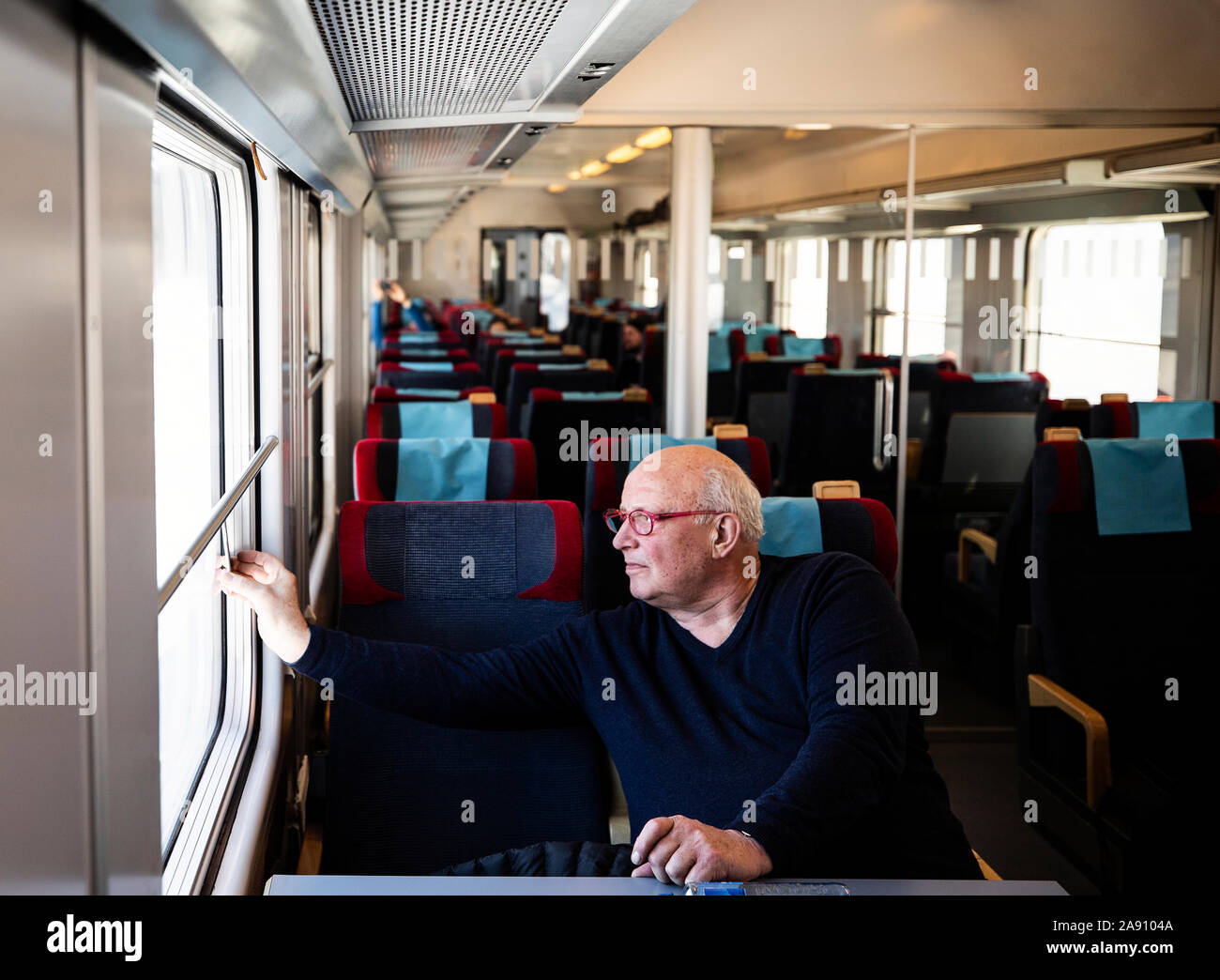 Senior à la recherche à travers la fenêtre du train Banque D'Images