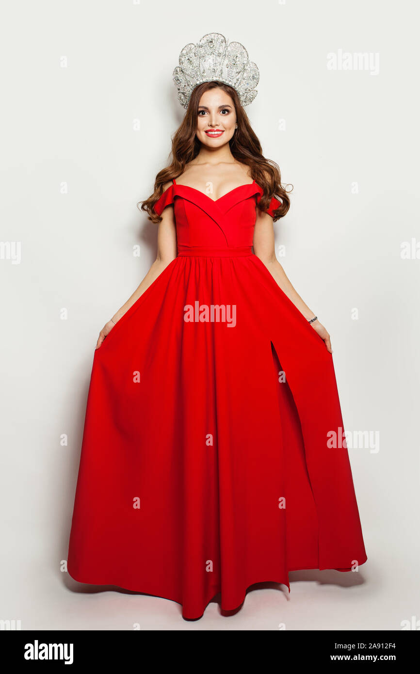 Modèle de mode femme en robe rouge soufflé et diamond couronne sur fond blanc. Portrait Banque D'Images