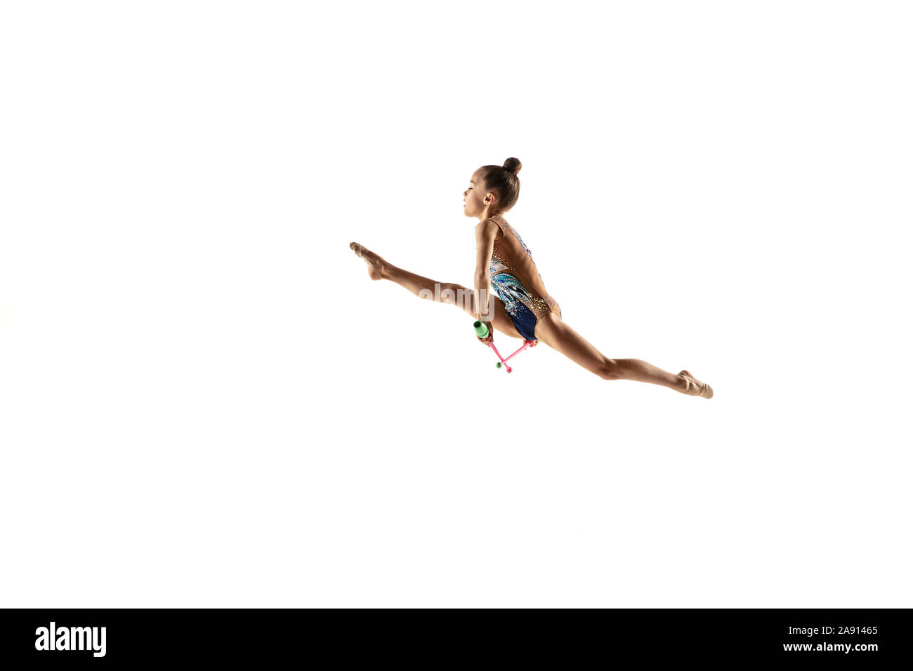 Petite fille souple isolé sur fond blanc studio. Peu de modèle féminin comme un artiste en gymnastique rythmique justaucorps lumineux. La grâce dans le mouvement, l'action et le sport. Faire des exercices avec les massues. Banque D'Images