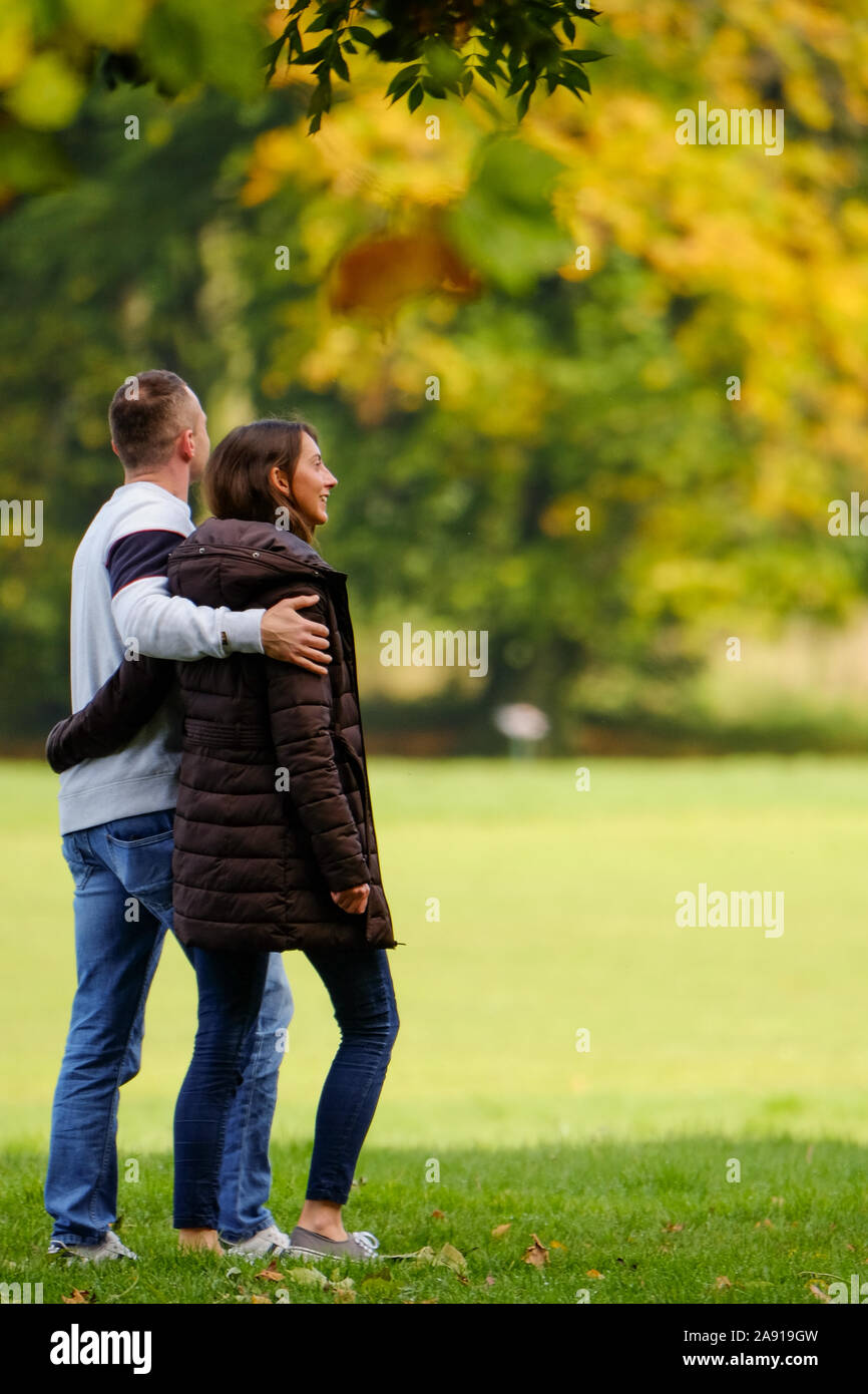 Jeune homme et femmes prenant une marche à travers le parc en automne Banque D'Images
