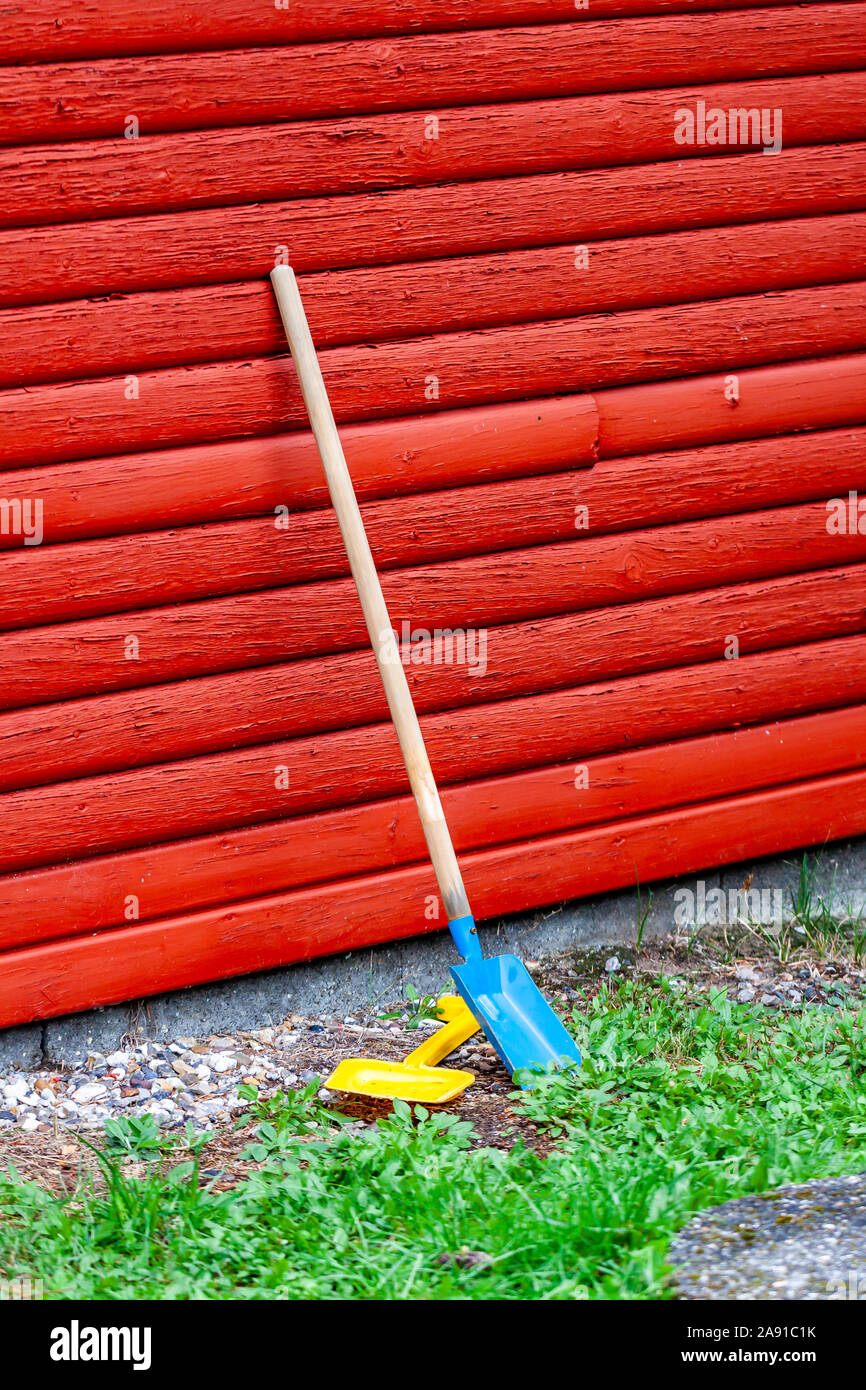 Toy pelle et vague debout à côté d'un mur en bois rouge. Banque D'Images