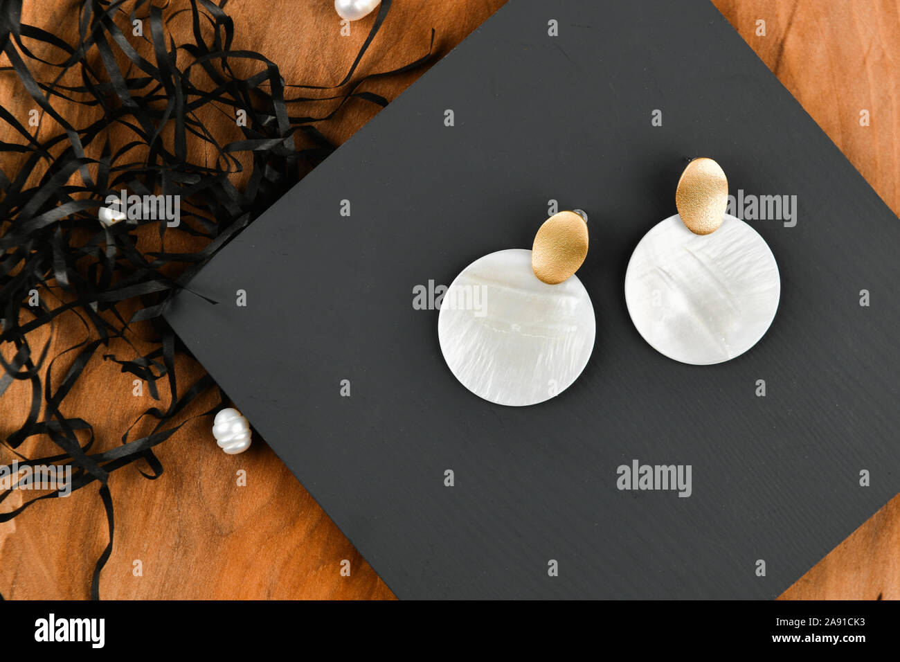 Boucles d blanc rond. Close-up. Loquet d'or. Disposés sur un support en bois. Vue de dessus. Le concept de bijoux et de joaillerie. Cadeaux Femmes Banque D'Images