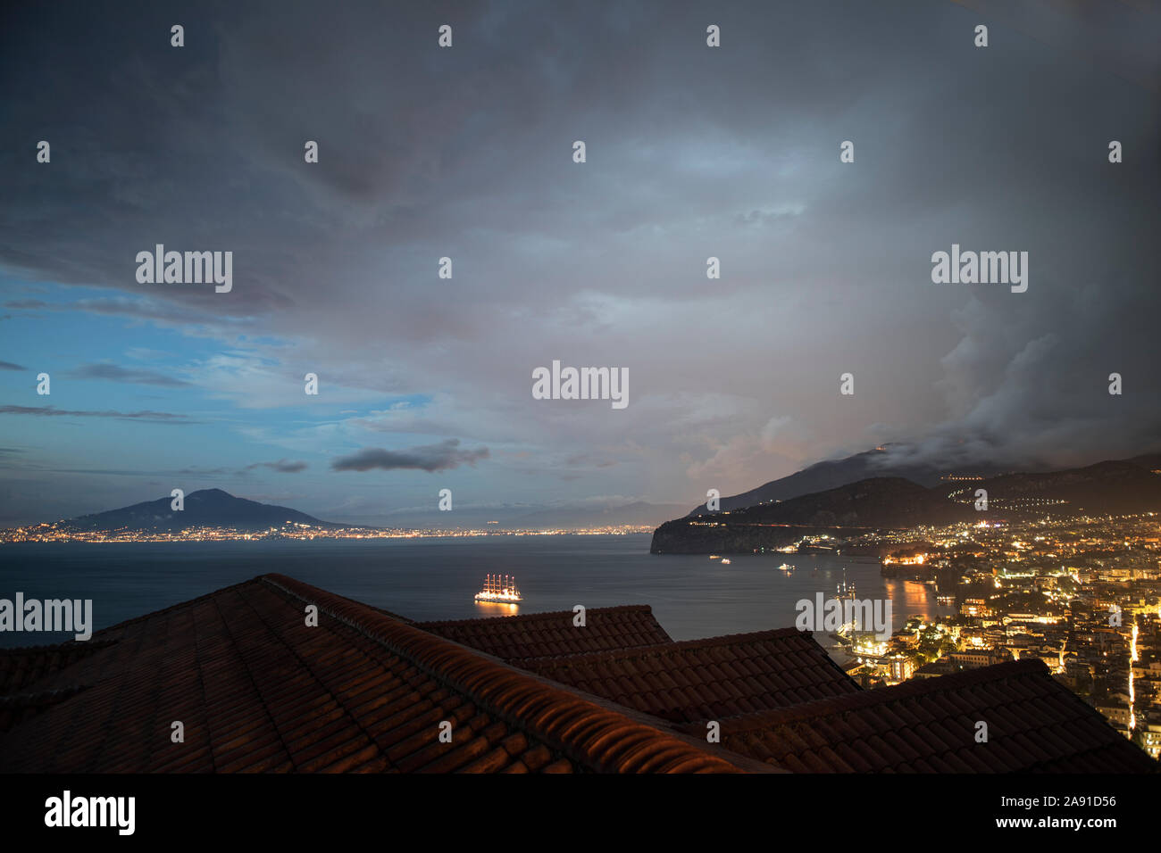 Éclairs de feuilles sur les toits de Sorrente, la baie de Naples et le Vésuve dans la lumière du soir, Italie. Banque D'Images