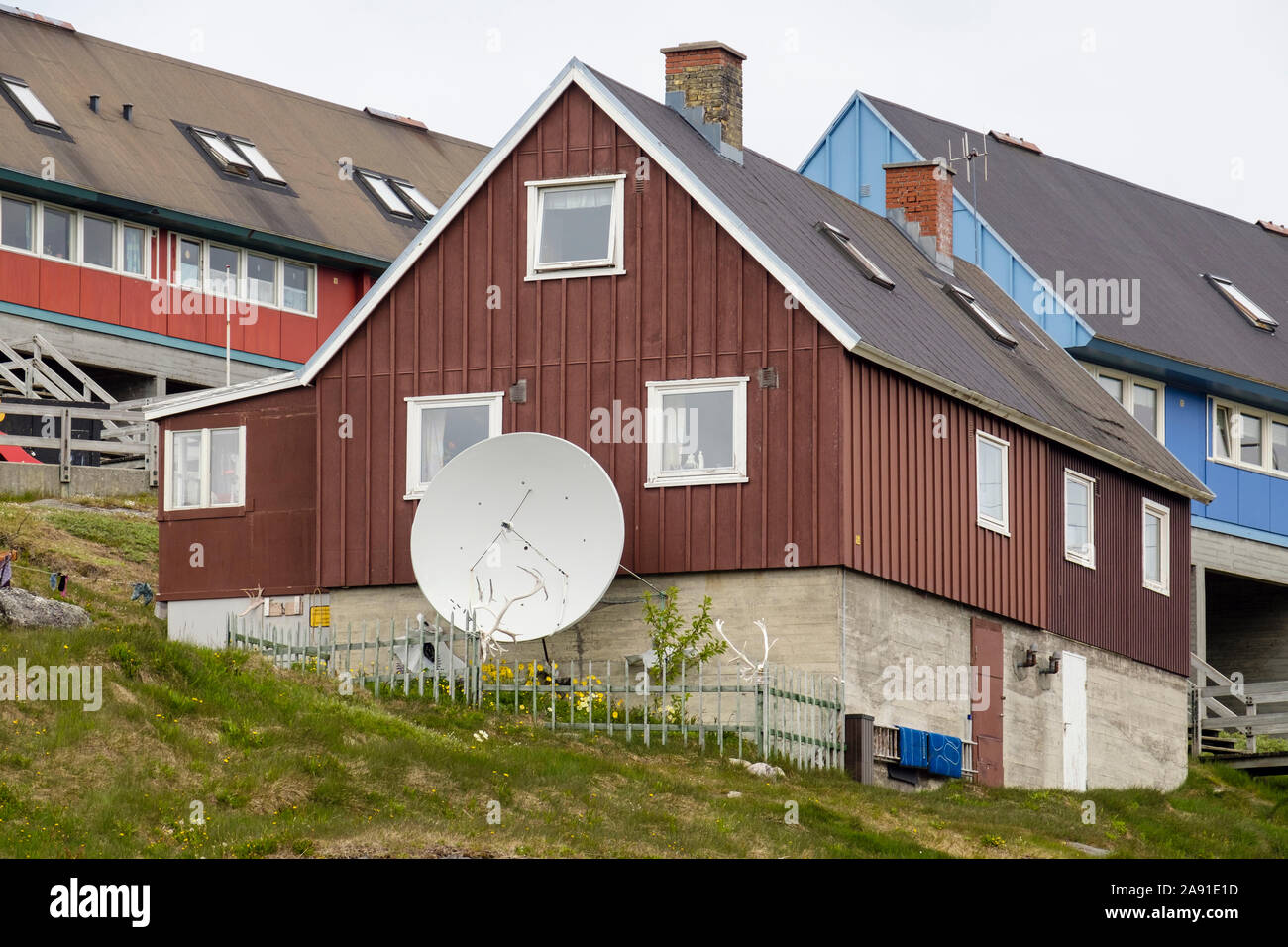 Grande antenne satellite à l'extérieur d'une maison typique des Inuits construit de bois et béton. Paamiut (Frederikshåb), Sermersooq, Groenland Banque D'Images
