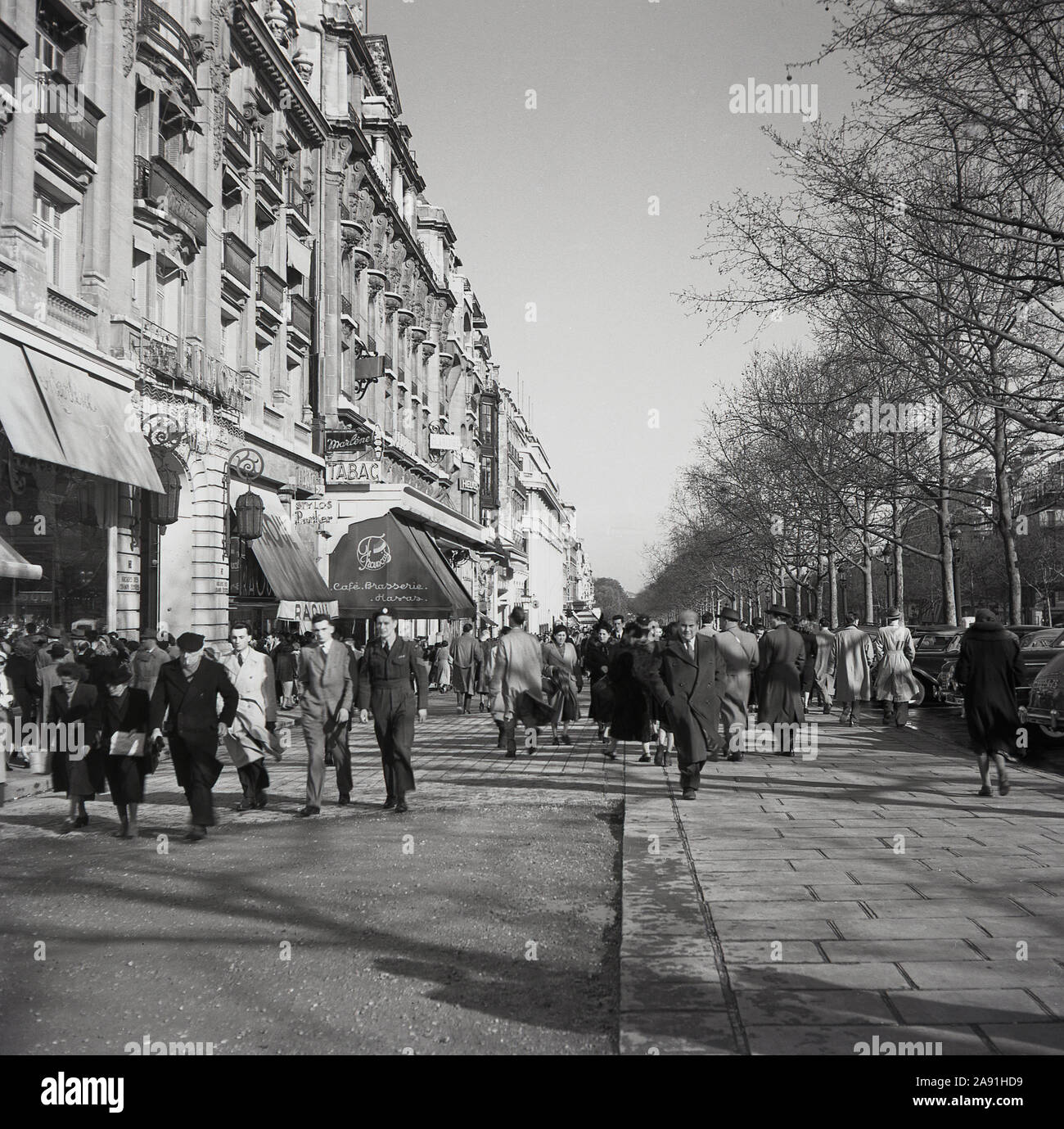 Années 1950, historique, le printemps et les parisiens dans leur manteau de marcher en haut de l'Avenue de Champs-Elysées, Paris, France. Banque D'Images
