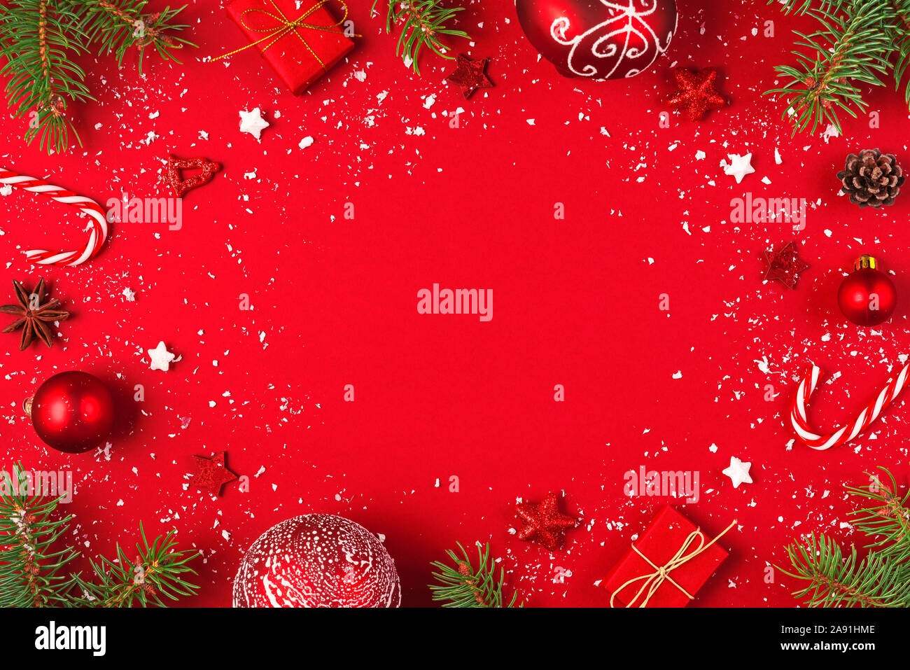 Noël ou bonne année fond rouge. Cadre fait de branches de sapins, décorations et coffrets cadeaux avec neige sur fond rouge. Télévision. Banque D'Images