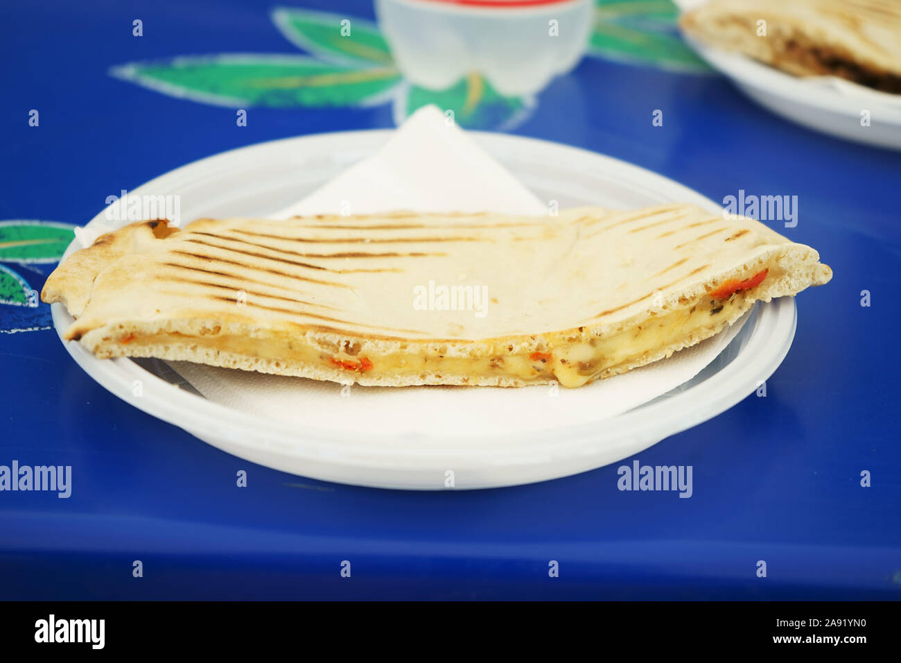 Pain plat - sandwich Piadina romagnola avec tomate et fromage sur plat en plastique Banque D'Images