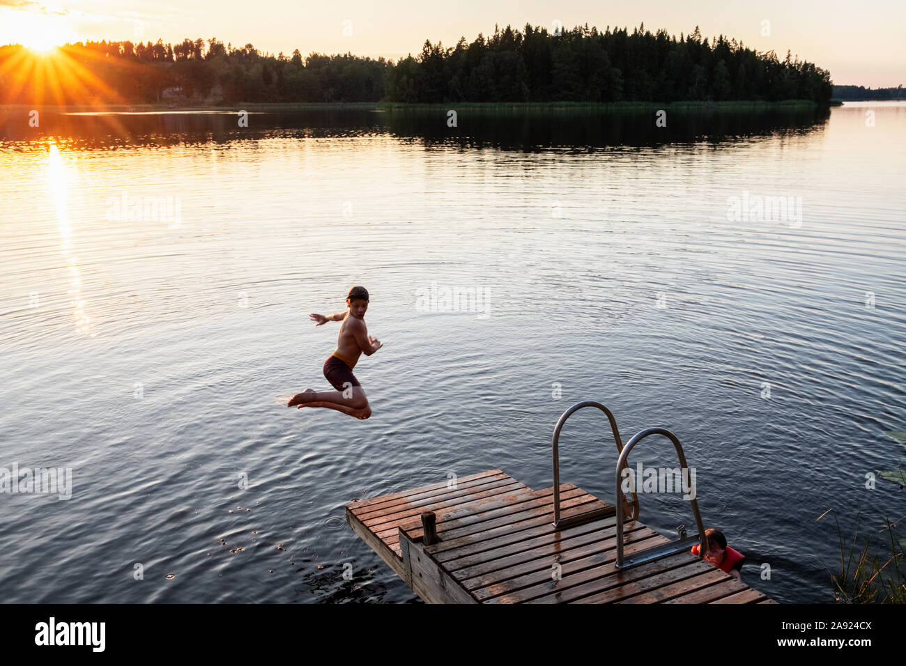 Garçon sautant dans le lac Banque D'Images