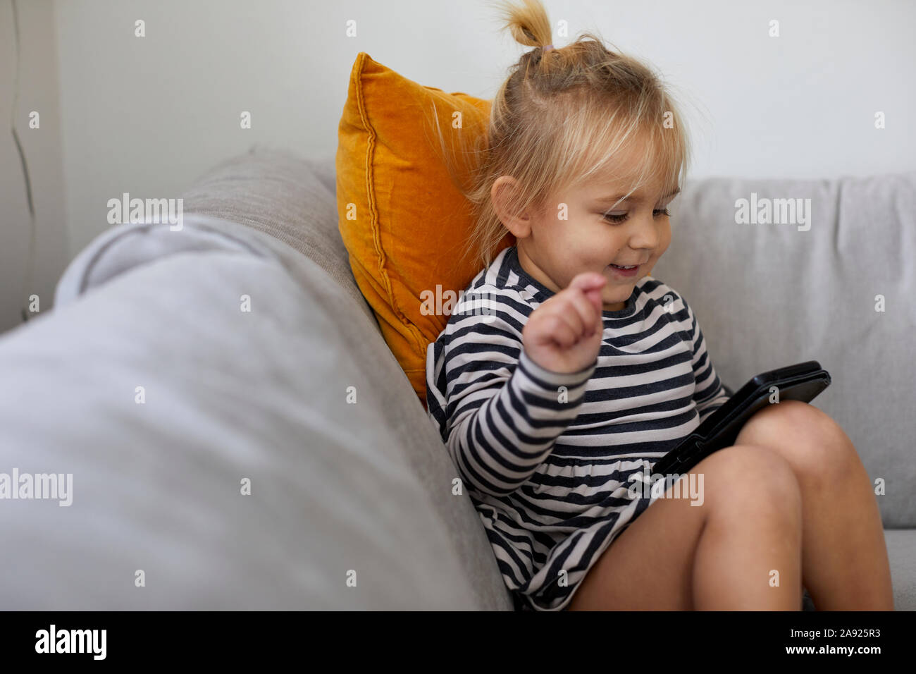 Girl on sofa using cell phone Banque D'Images