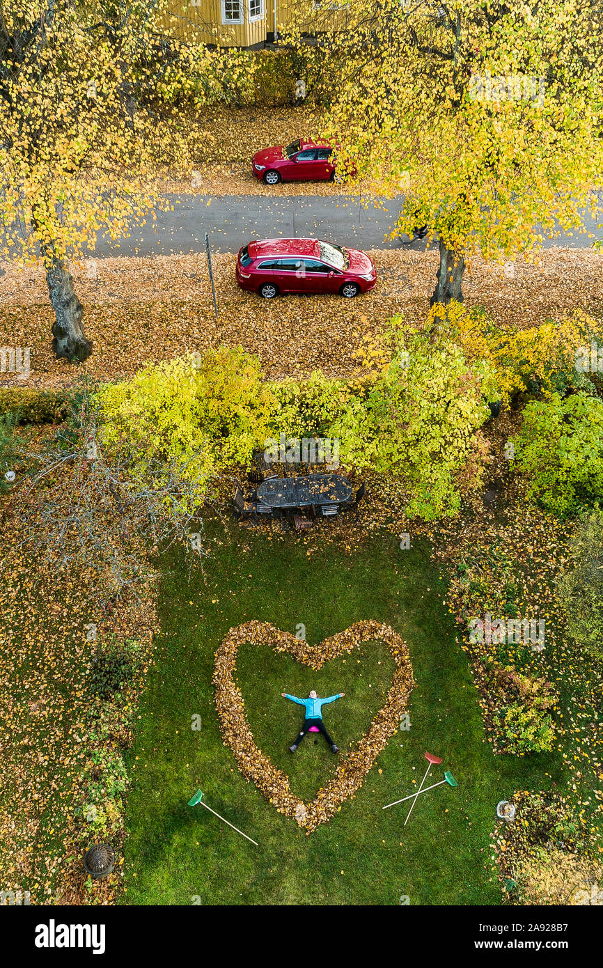 Personne couchée dans coeur faits de feuilles tombées Banque D'Images