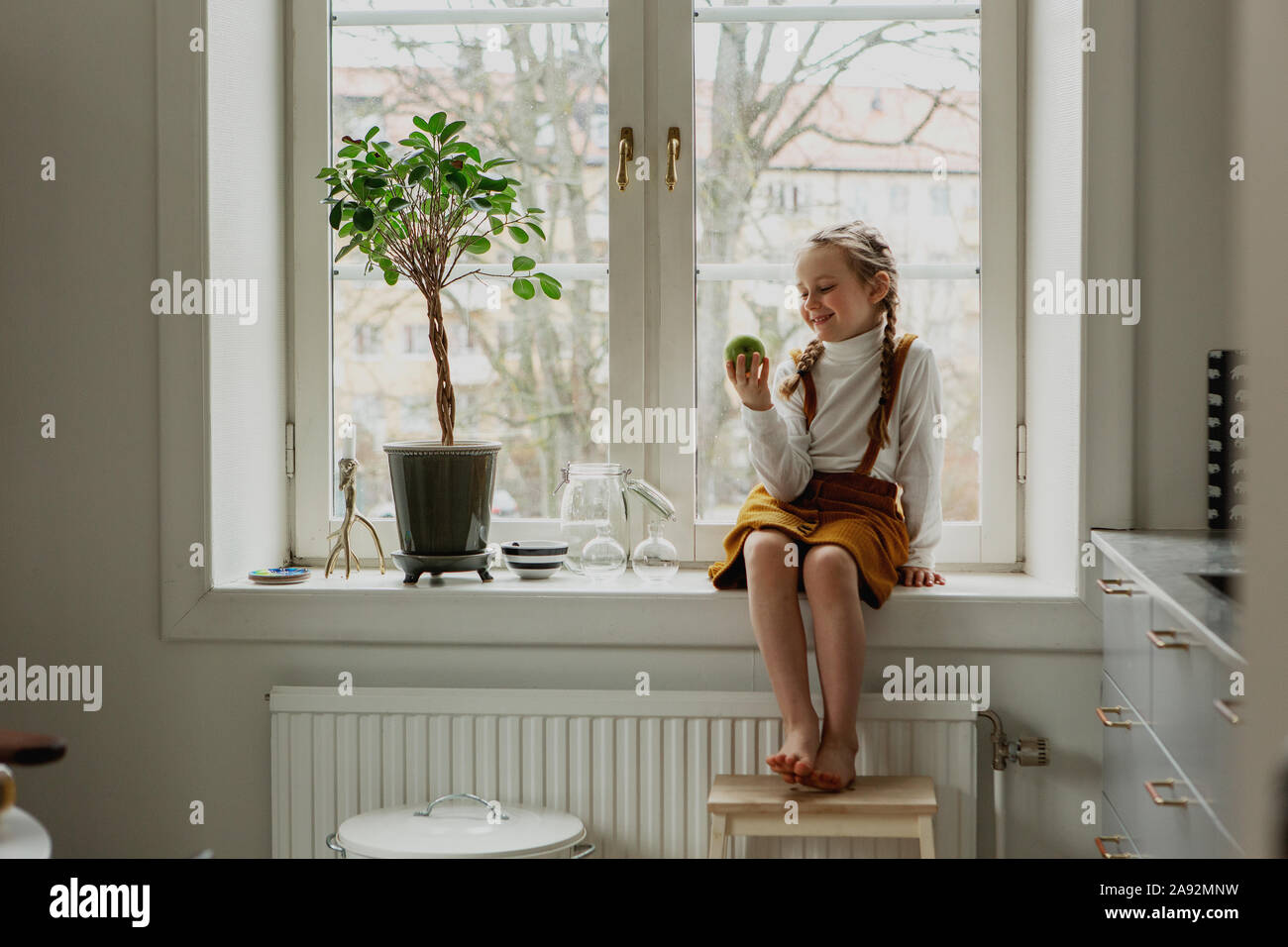 Smiling girl sitting on windowsill Banque D'Images