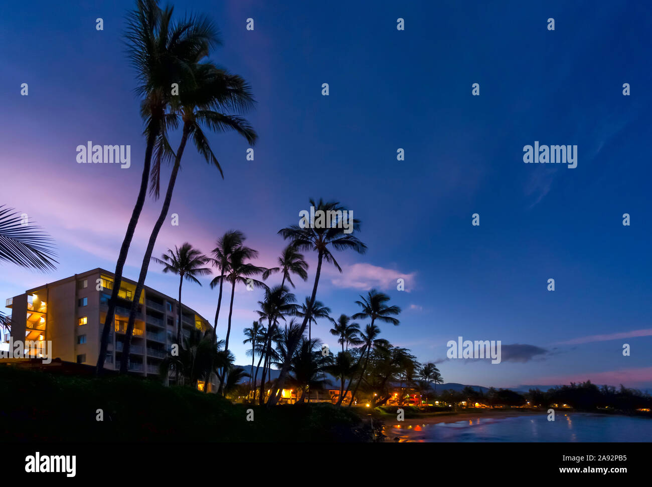Hôtels et palmiers le long de la côte au coucher du soleil, Kamaole une et deux plages, Kamaole Beach Park; Kihei, Maui, Hawaii, États-Unis d'Amérique Banque D'Images