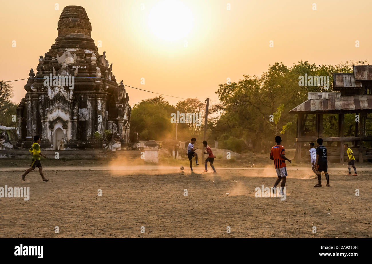 Garçons jouant au football au coucher du soleil; Bagan, région de Mandalay, Myanmar Banque D'Images