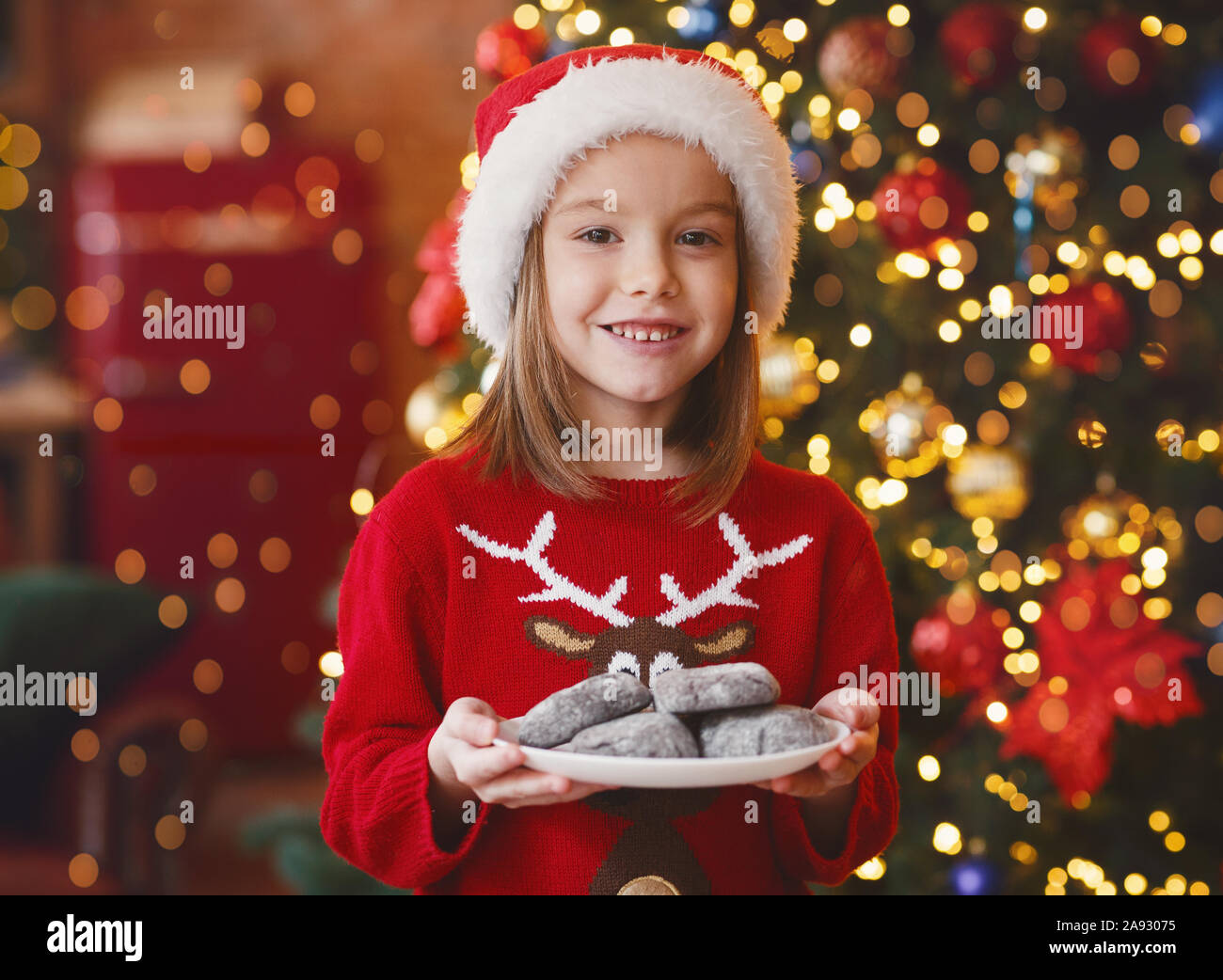 Cheerful girl maintenant la plaque avec les cookies pour le père noël Banque D'Images