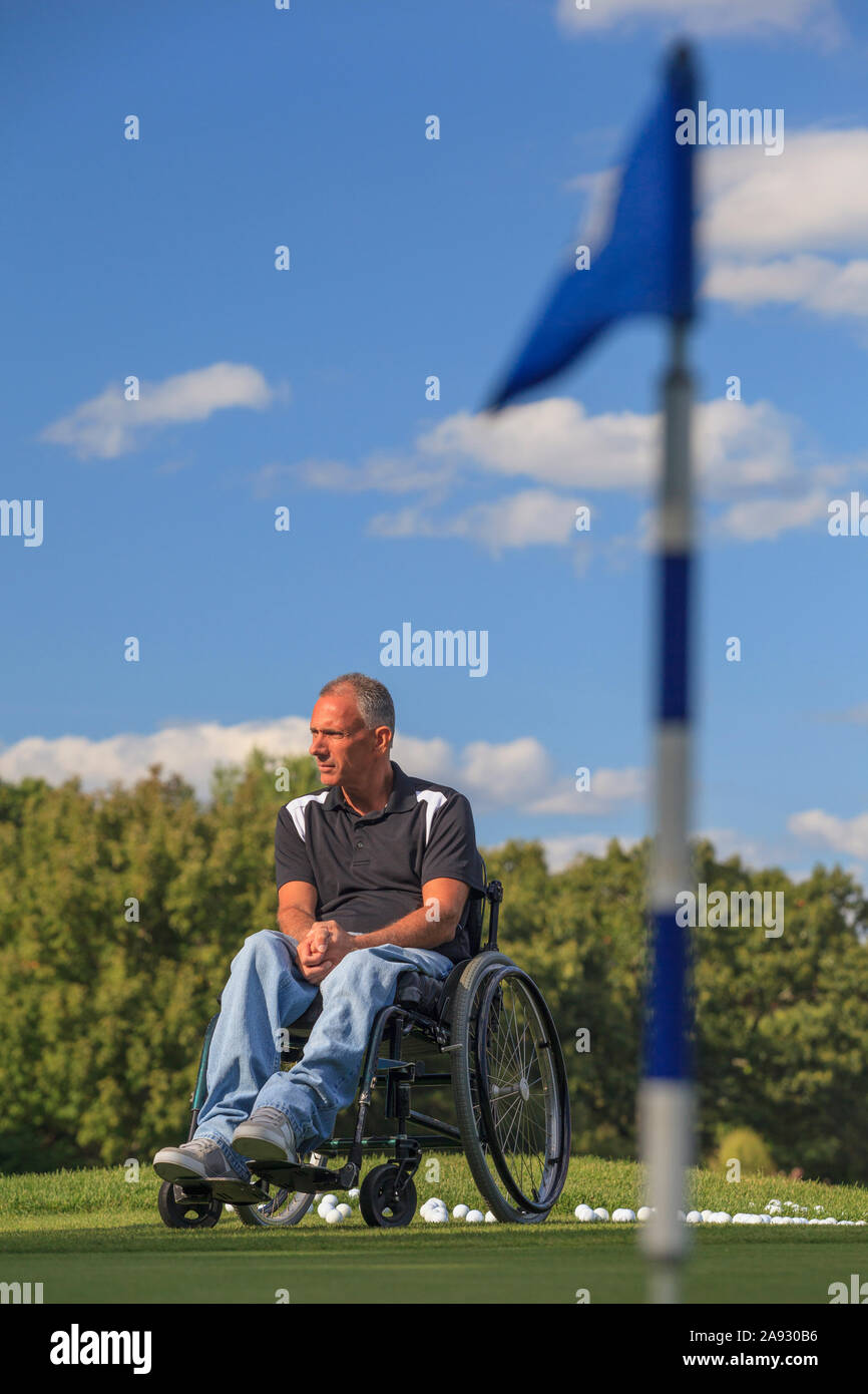 Homme blessé à la moelle épinière dans un fauteuil roulant en attente de jouer au golf Banque D'Images