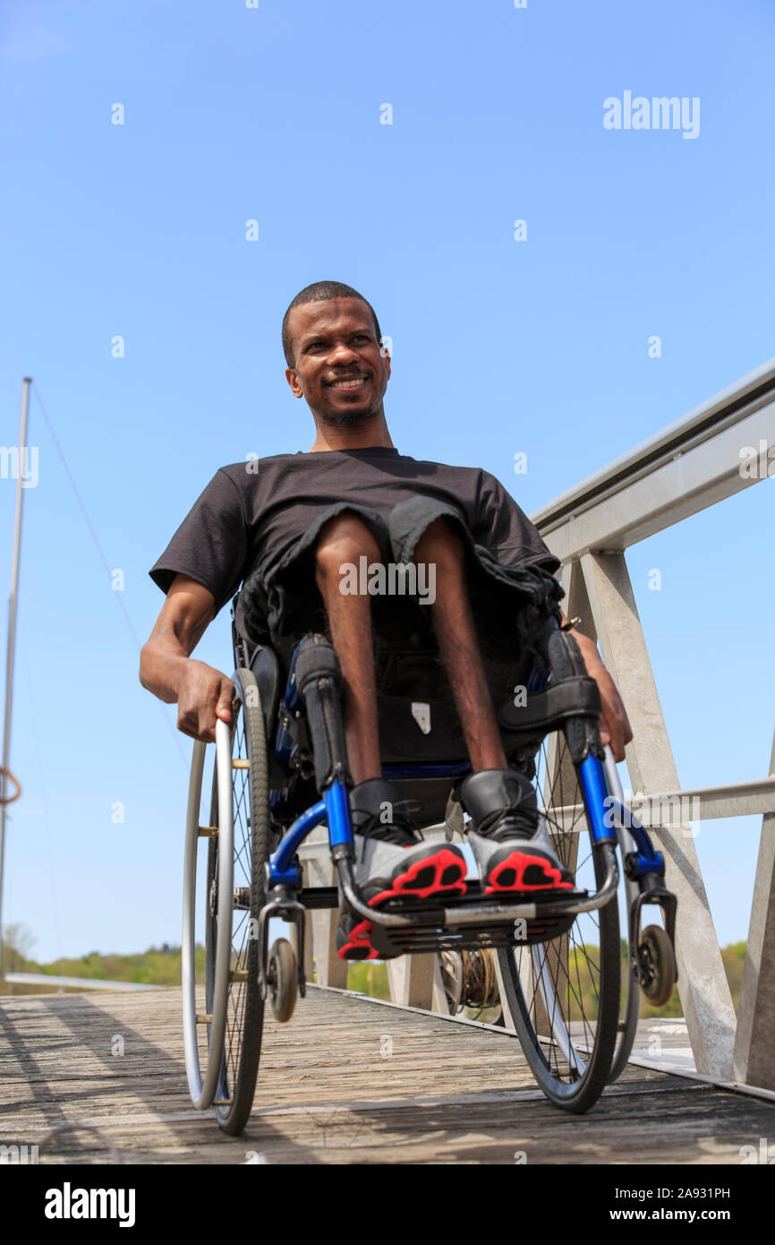 Homme en fauteuil roulant qui avait une méningite spinale en baisse une rampe d'accès à un quai Banque D'Images