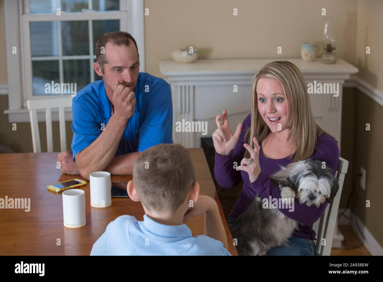 Une famille ayant une déficience auditive, disant en American Sign Language « Basketball » avec un chien à la maison Banque D'Images