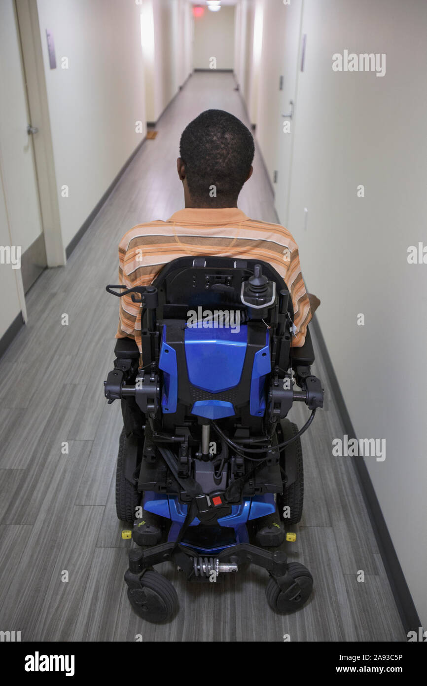 Homme avec le syndrome de Guillain-barre dans le couloir de l'appartement sur son chaise haute Banque D'Images