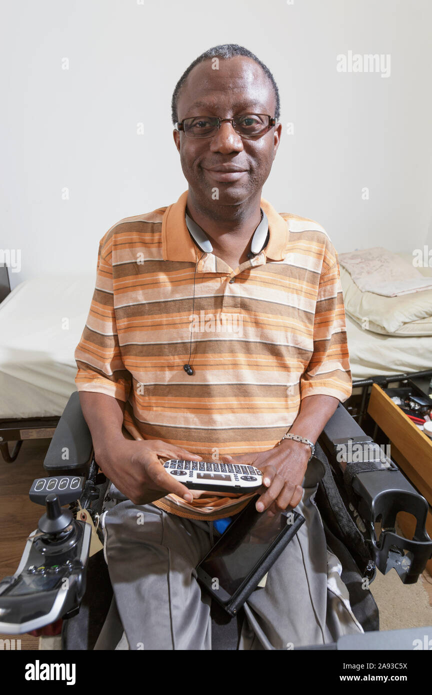 Homme avec le syndrome de Guillain-barre en utilisant son mini-clavier Bluetooth sa chaise haute à la maison Banque D'Images