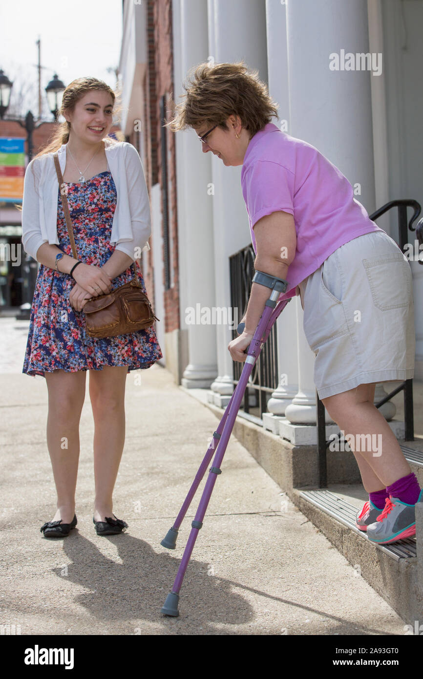 Femme atteinte de paralysie cérébrale descendant les escaliers pendant que sa sœur attend Banque D'Images