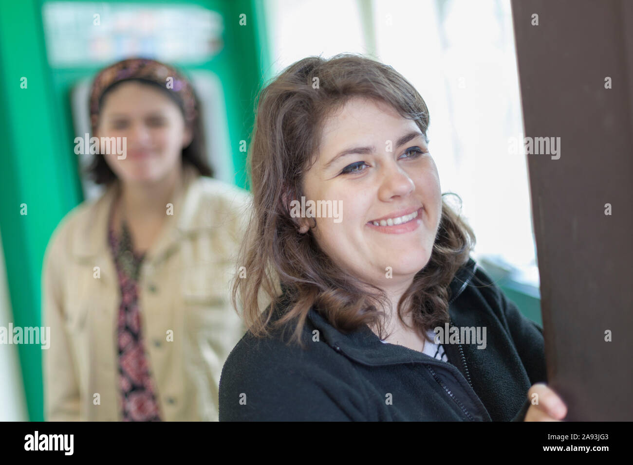 Deux amies qui utilisent un ATM, une avec une lésion cérébrale traumatique et une Amputee Banque D'Images