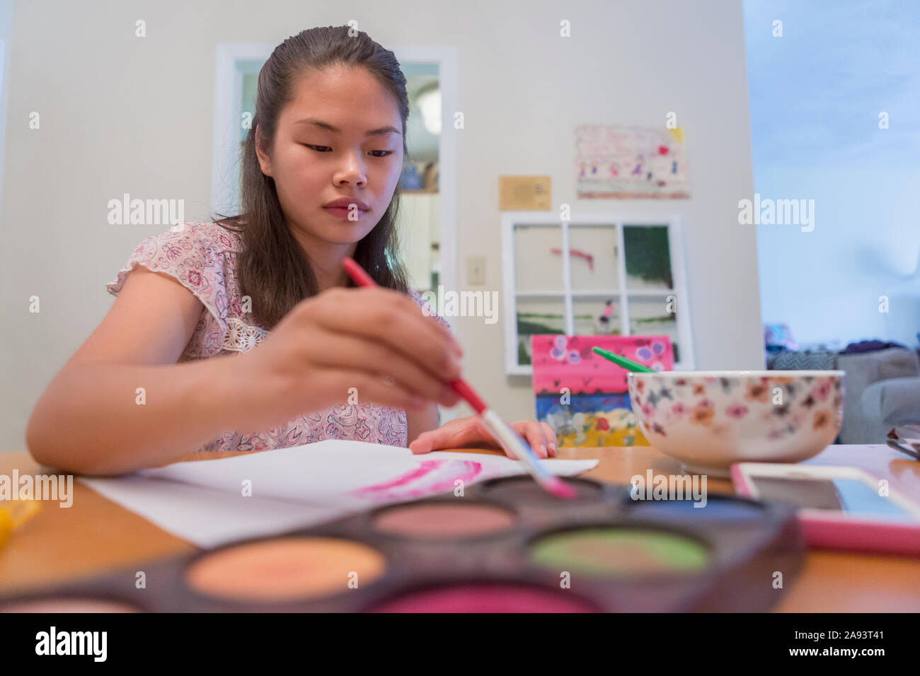Jeune fille avec un handicap d'apprentissage utilisant des peintures Banque D'Images