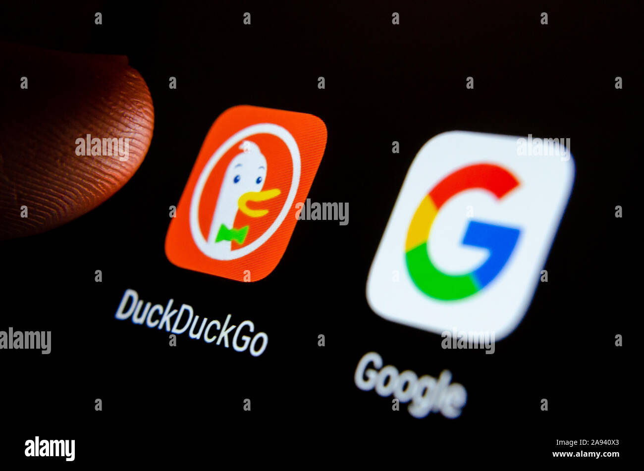 DuckDuckGo smartphone app sur un écran à côté de Google search et un doigt de le toucher. Focus sélectif. Banque D'Images