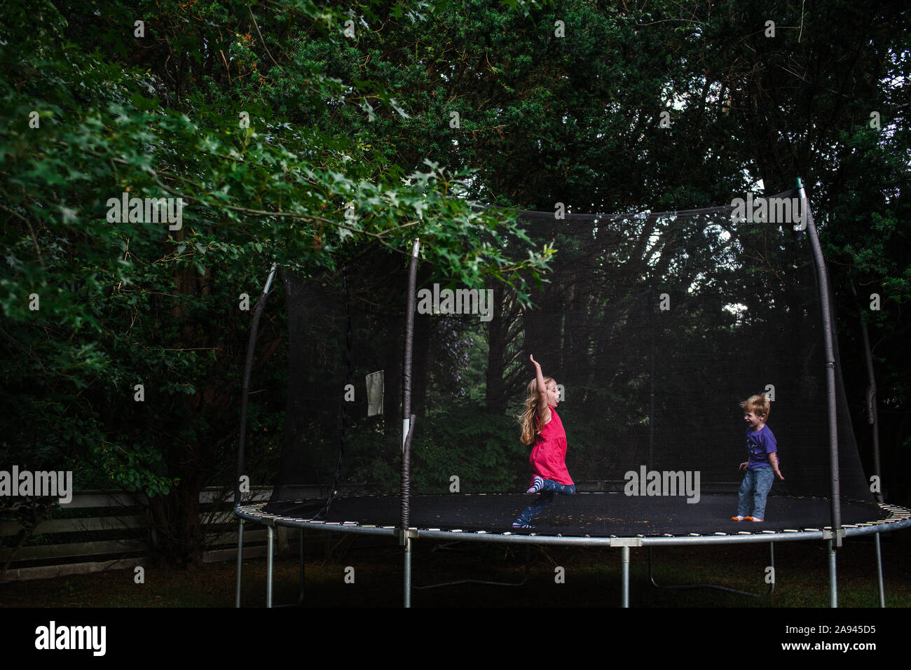 Une fille et garçon sauter sur un trampoline en plein air Photo Stock -  Alamy